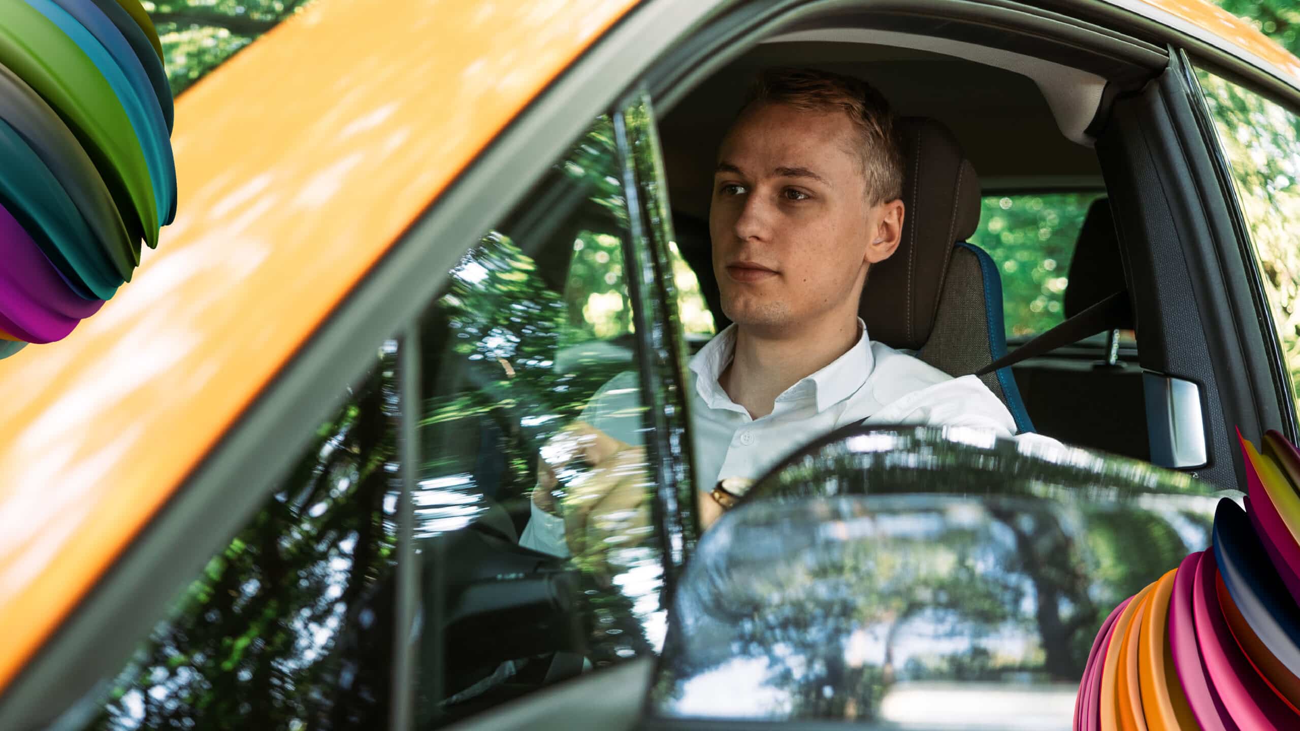 Image of a young man driving a yellow car.