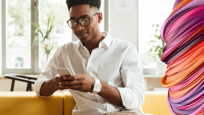 Young man wearing a white shirt is looking down at his phone screen.