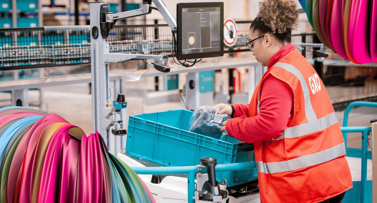 A extended worker wearing an orange overcoat sorts items at a seasonal job.