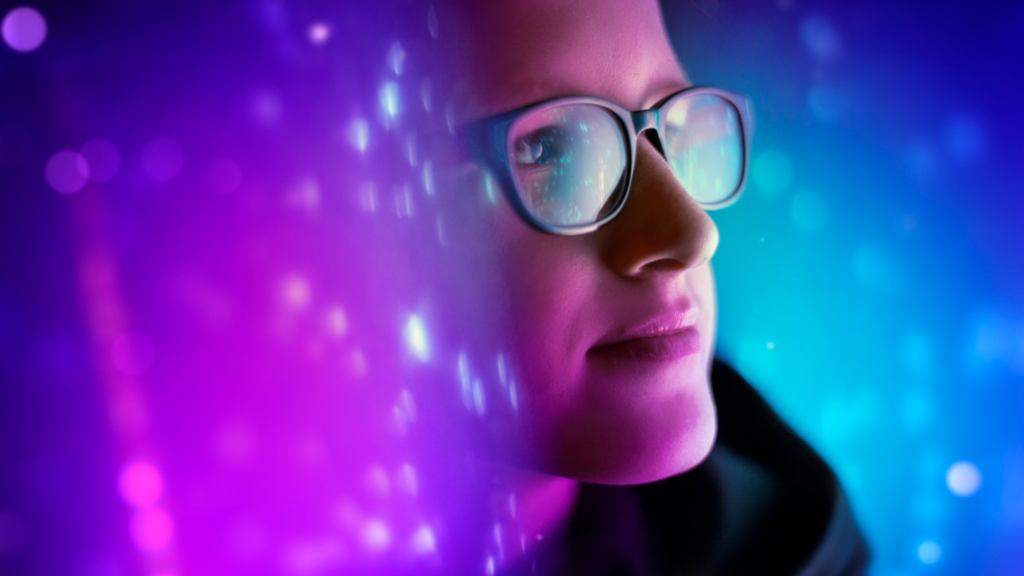 A young woman wearing glasses surrounded by futuristic light and colors looks up introspectively.