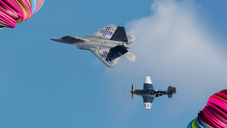 two planes flying - a fighter jet with Flextrack branding and an older model that has a hard time keeping up.